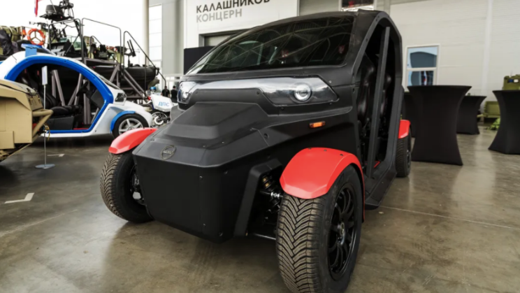 A black and red electric car sits in a garage.